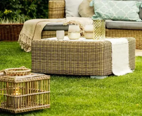Outdoor wicker furniture with candles on grass.