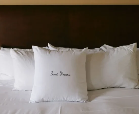 White pillows on bed, one says 'Sweet Dreams'.